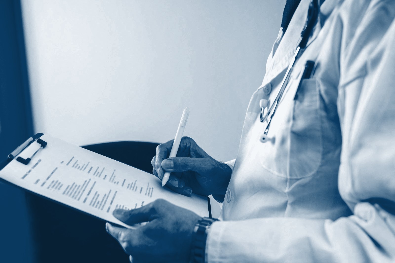 Clinician writing on a patient notes clipboard